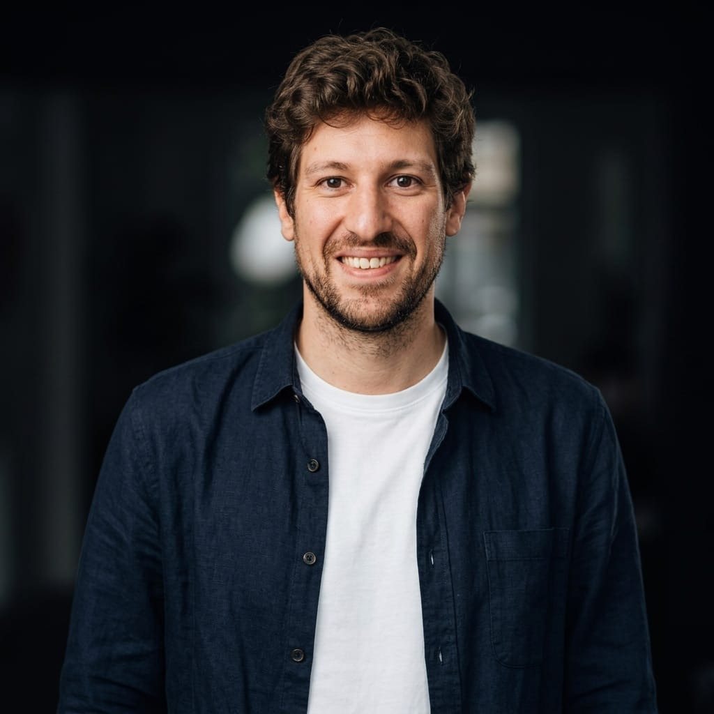 Retrato de Carlos Tomás Ferrer, Charlie, sonriendo con camisa azul marino sobre fondo oscuro.